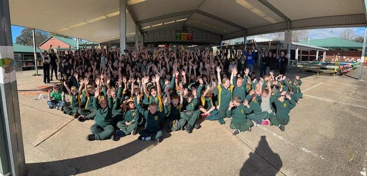 Whole school group photo of Franklin Public School students and staff raising their hands.