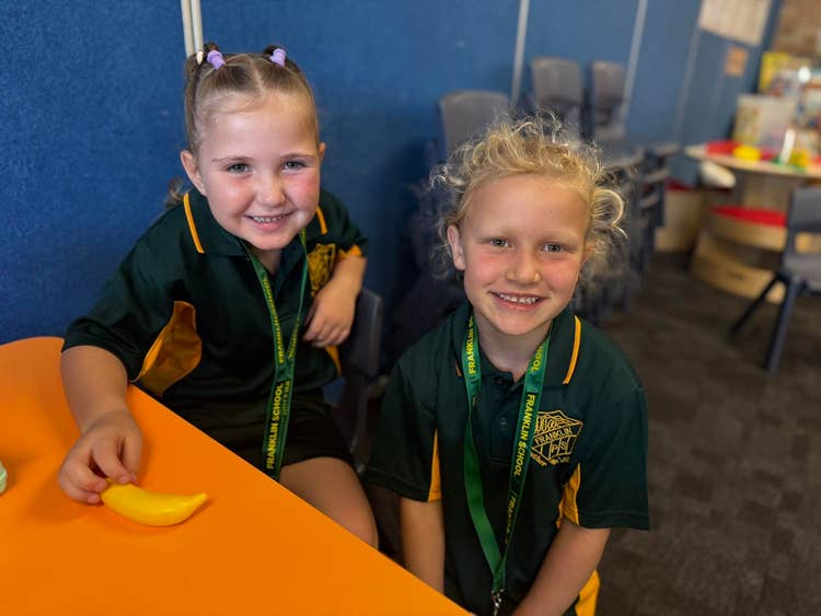 Two Kindergarten students sitting at a desk in the classroom.